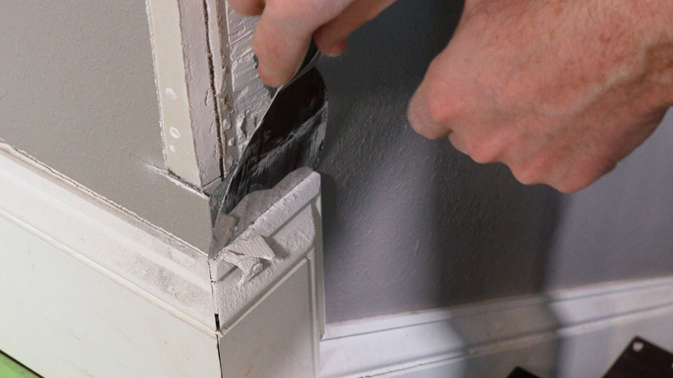 using a joint knife to scrape away old compound.